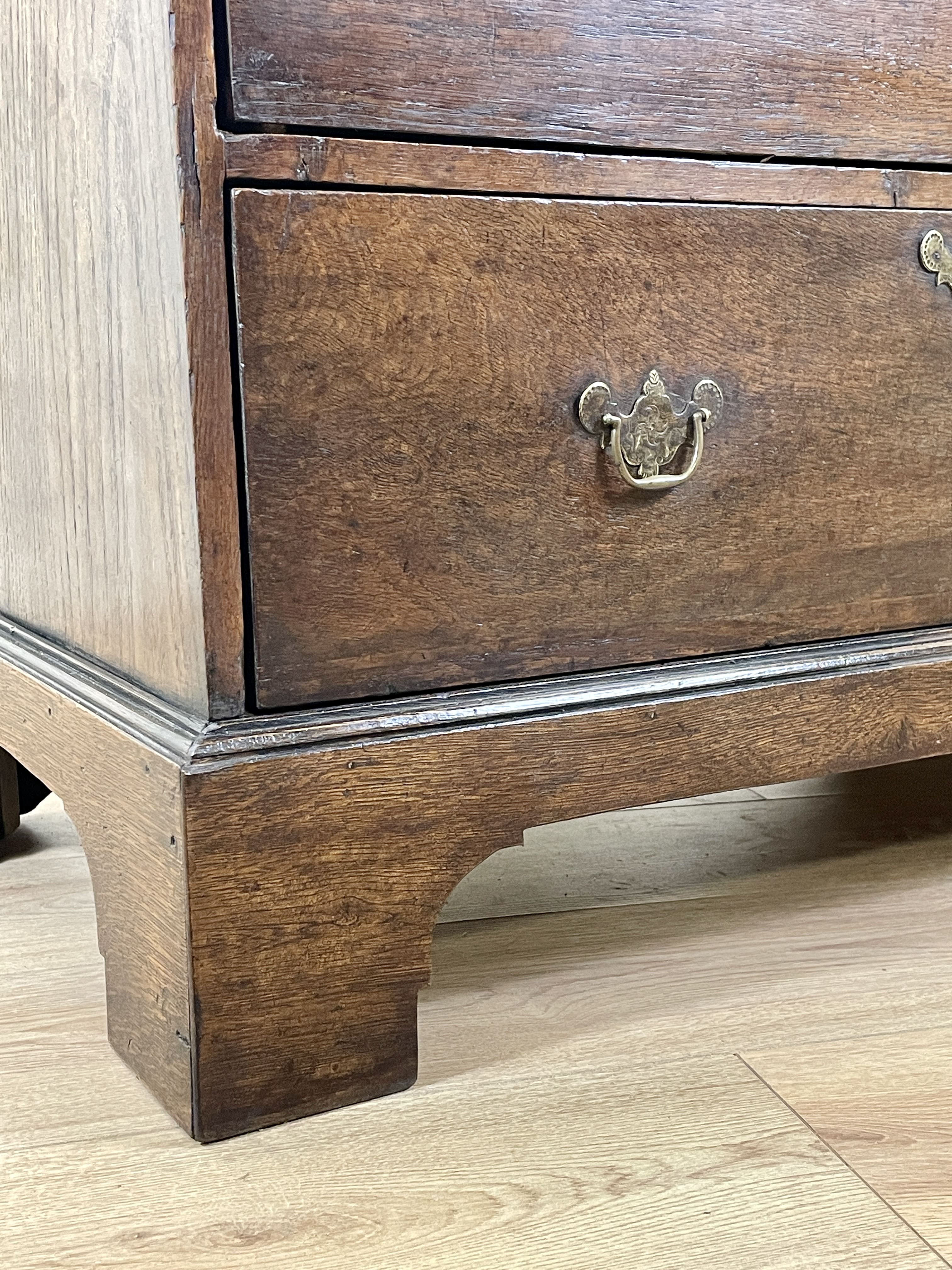 Mid-18th century antique Georgian oak chest of drawers with caddy moulded top, two short and three long graduated drawers, original brass handles, and bracket feet.