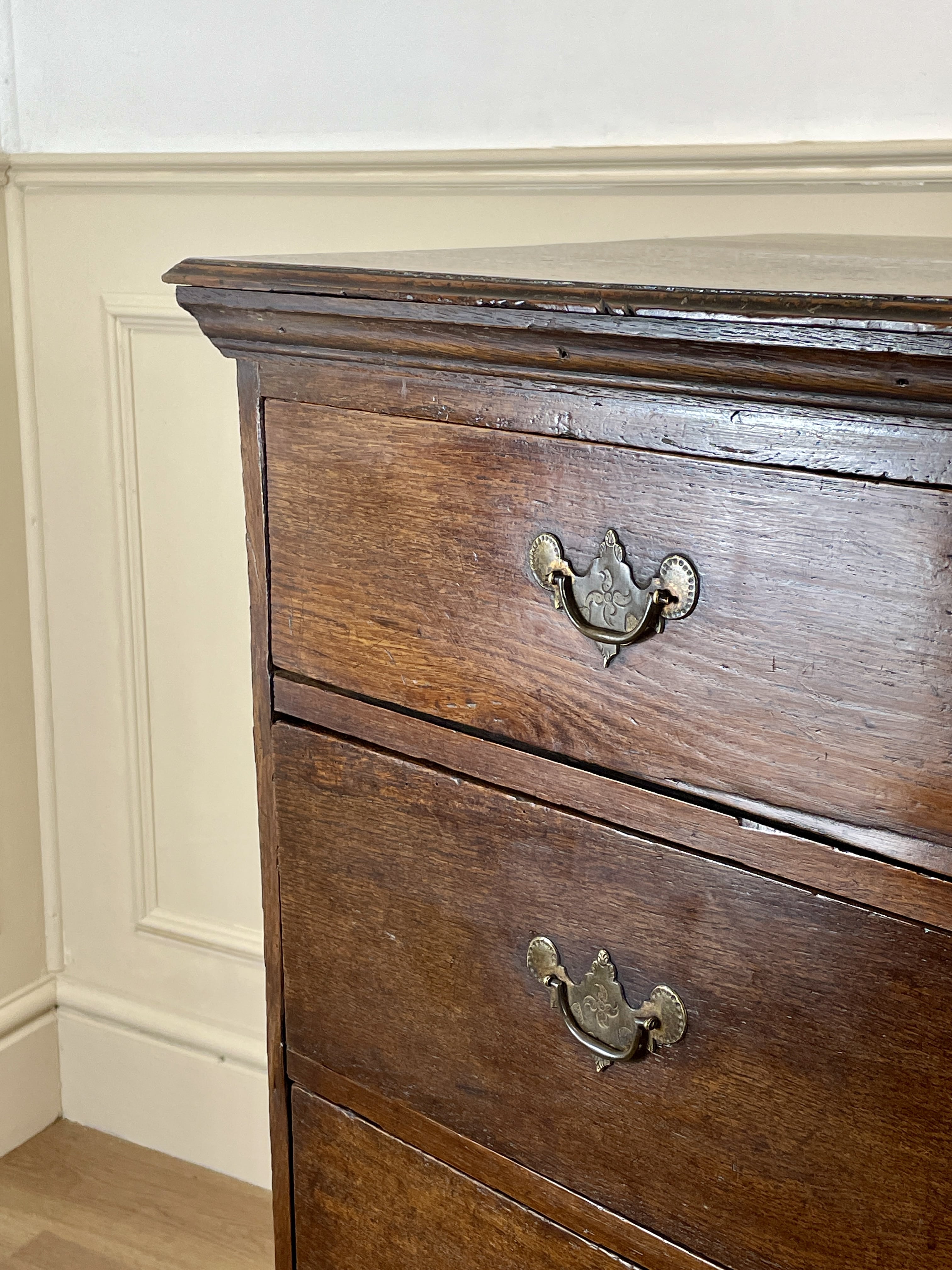 Mid-18th century antique Georgian oak chest of drawers with caddy moulded top, two short and three long graduated drawers, original brass handles, and bracket feet.