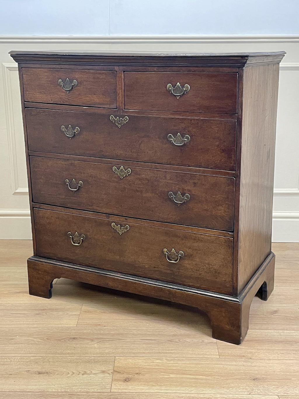 Mid-18th century antique Georgian oak chest of drawers with caddy moulded top, two short and three long graduated drawers, original brass handles, and bracket feet.