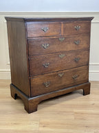 Mid-18th century antique Georgian oak chest of drawers with caddy moulded top, two short and three long graduated drawers, original brass handles, and bracket feet.