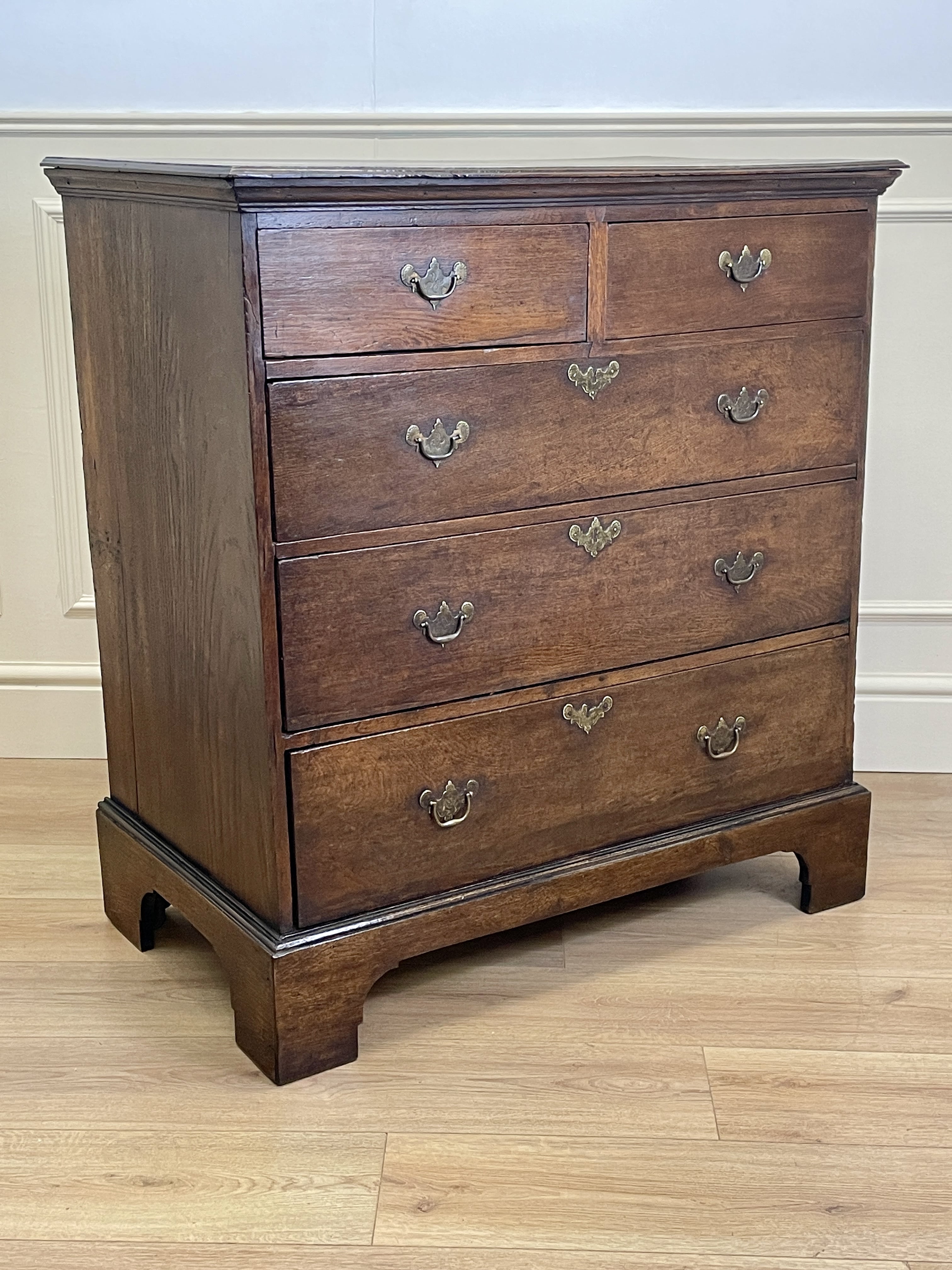 Mid-18th century antique Georgian oak chest of drawers with caddy moulded top, two short and three long graduated drawers, original brass handles, and bracket feet.