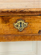 Wooden drawer with a decorative brass lock on a white wall.