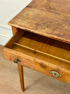 Wooden desk with an open drawer on a wooden floor.