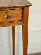 Vintage wooden side table with a single drawer against a neutral background