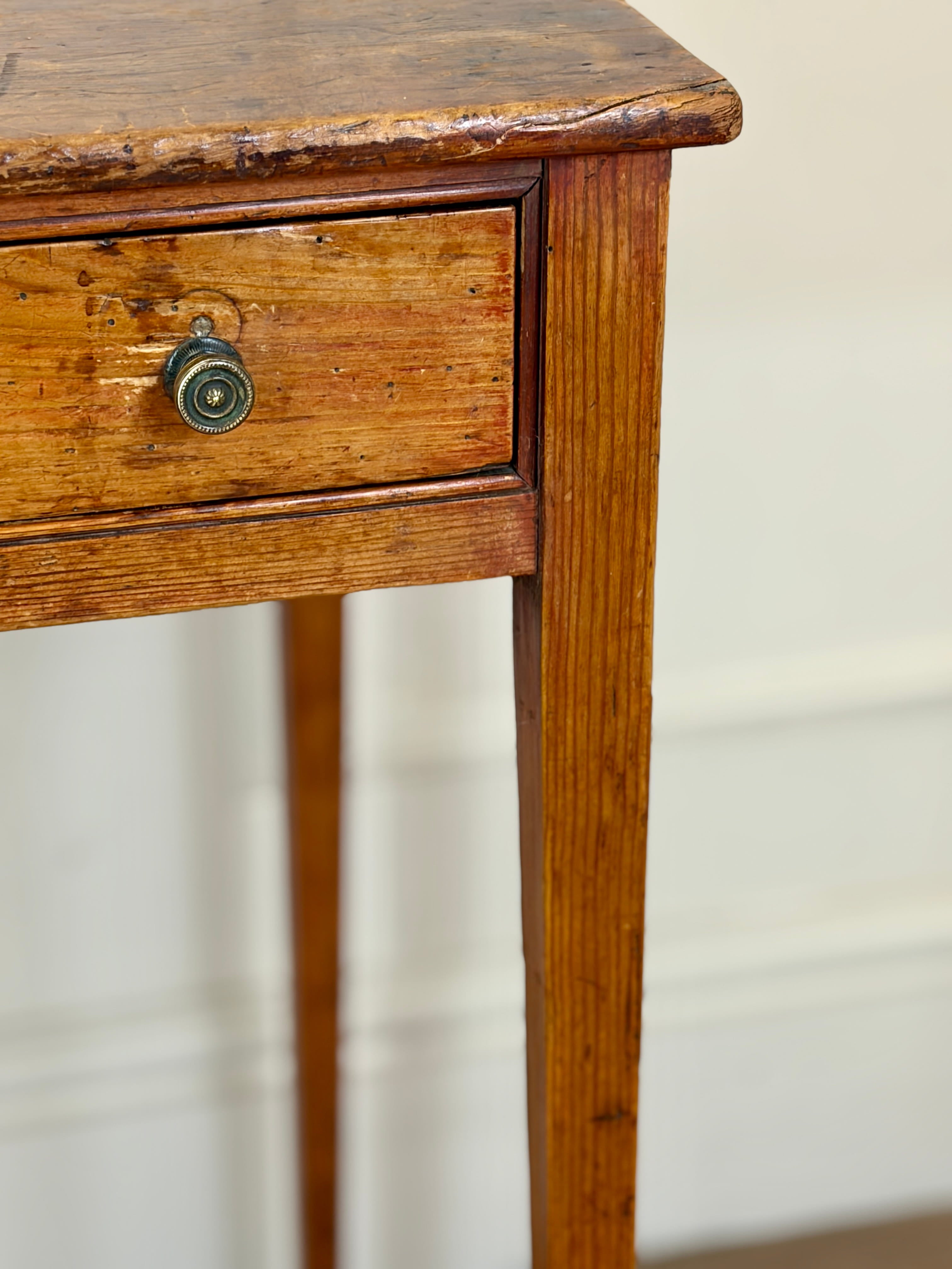 Vintage wooden side table with a single drawer against a neutral background