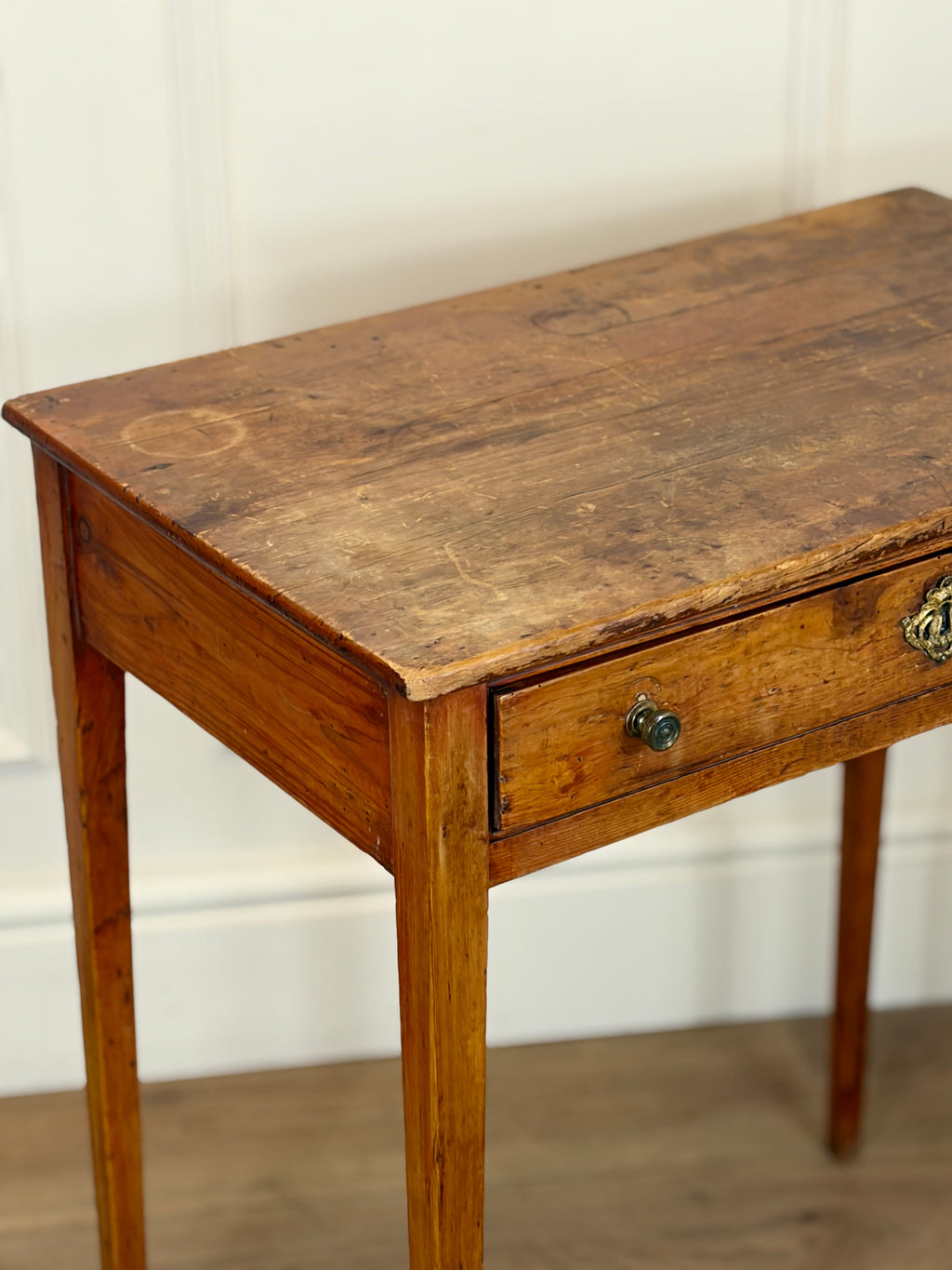 Wooden table with a single drawer against a white wall