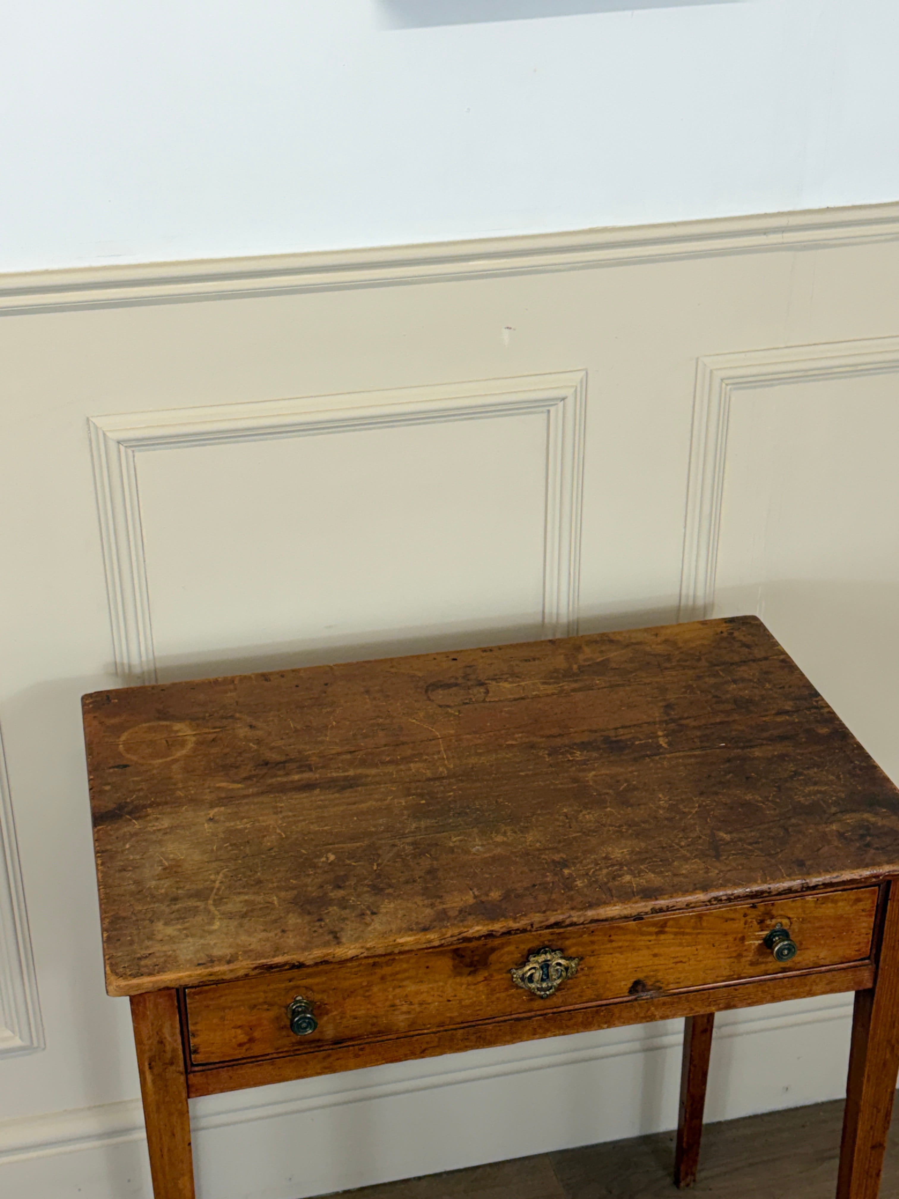 Wooden side table against a white paneled wall