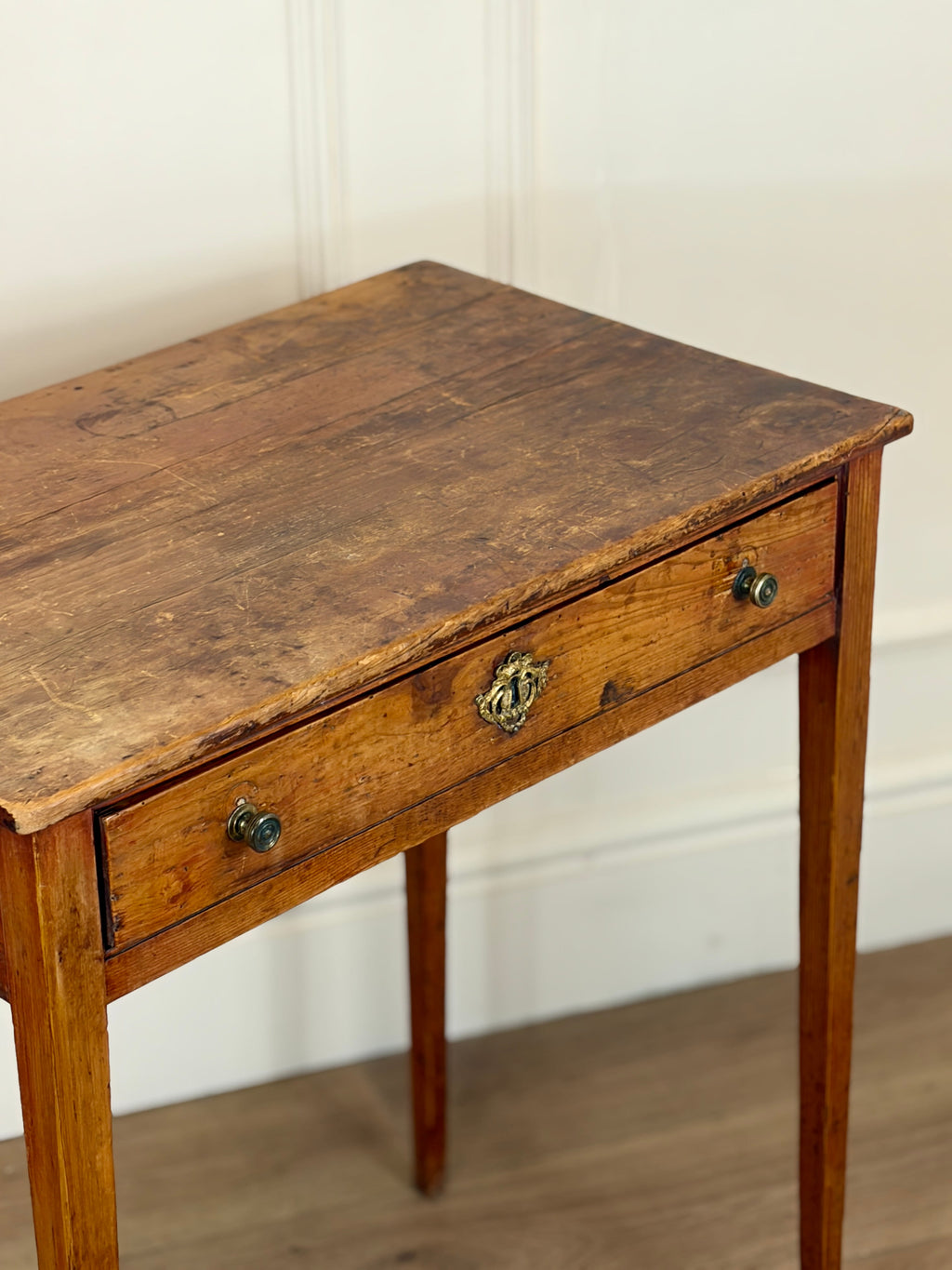 Wooden table with a single drawer against a white wall
