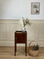 Wooden side table with decorative items against a wall with wainscoting.