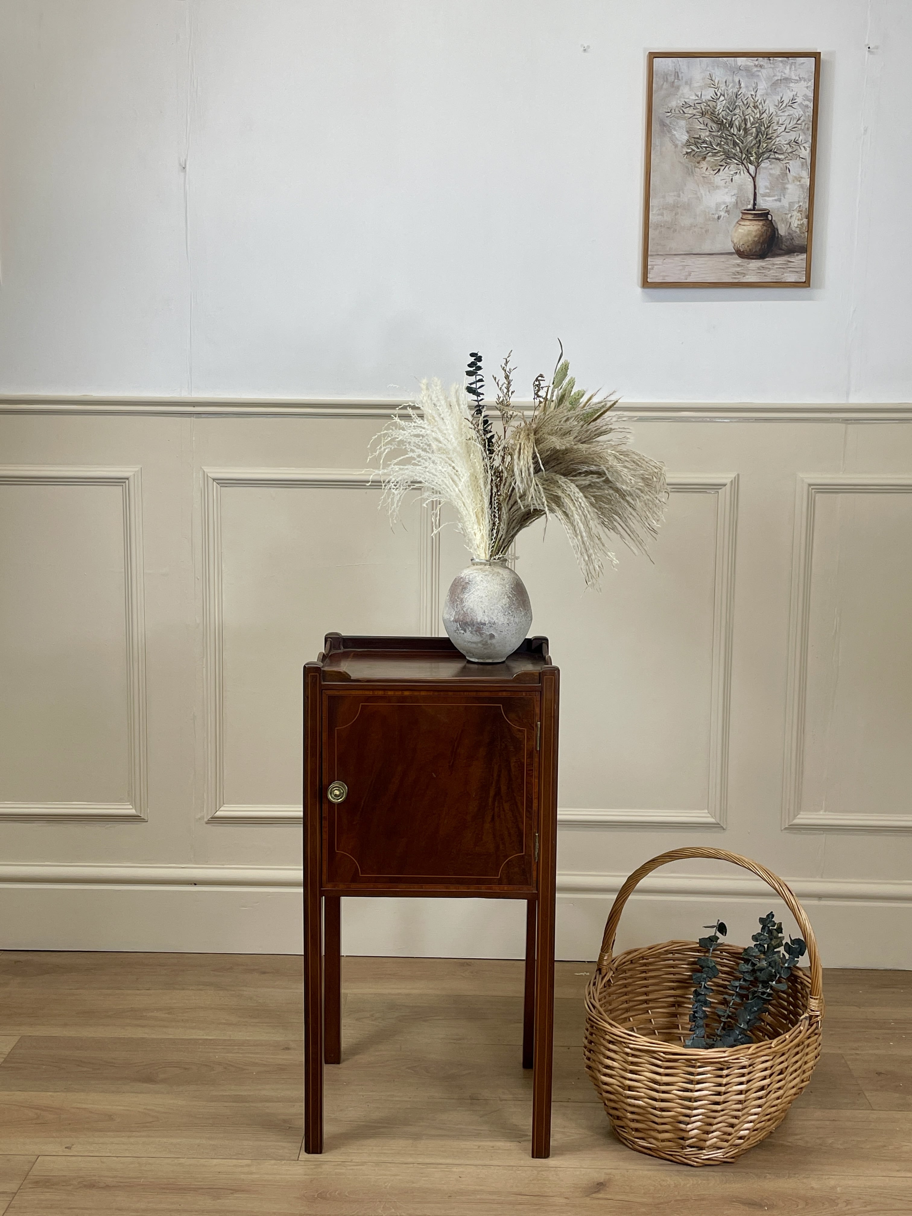 Wooden side table with decorative items against a wall with wainscoting.