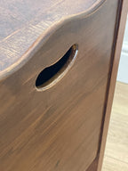Wooden drawer with a round metal handle on a wooden surface.