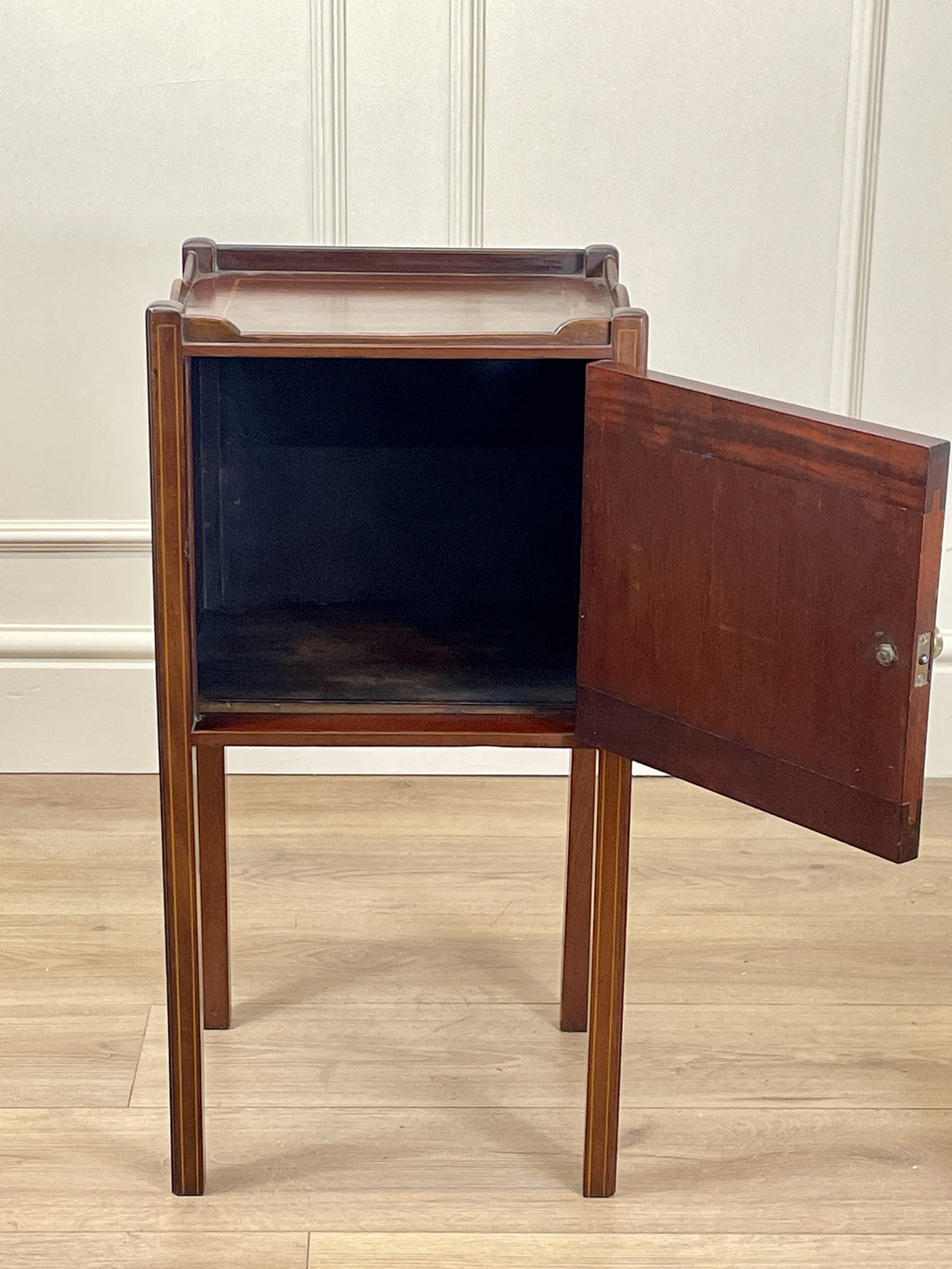 Wooden side table with open door on a wooden floor