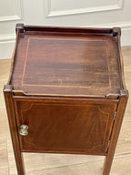 Wooden side table with a door on a wooden floor.