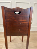 Wooden headboard with a handle on a wooden floor against a white wall.