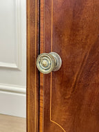 Close-up of a wooden door with brass doorknobs on a white wall background