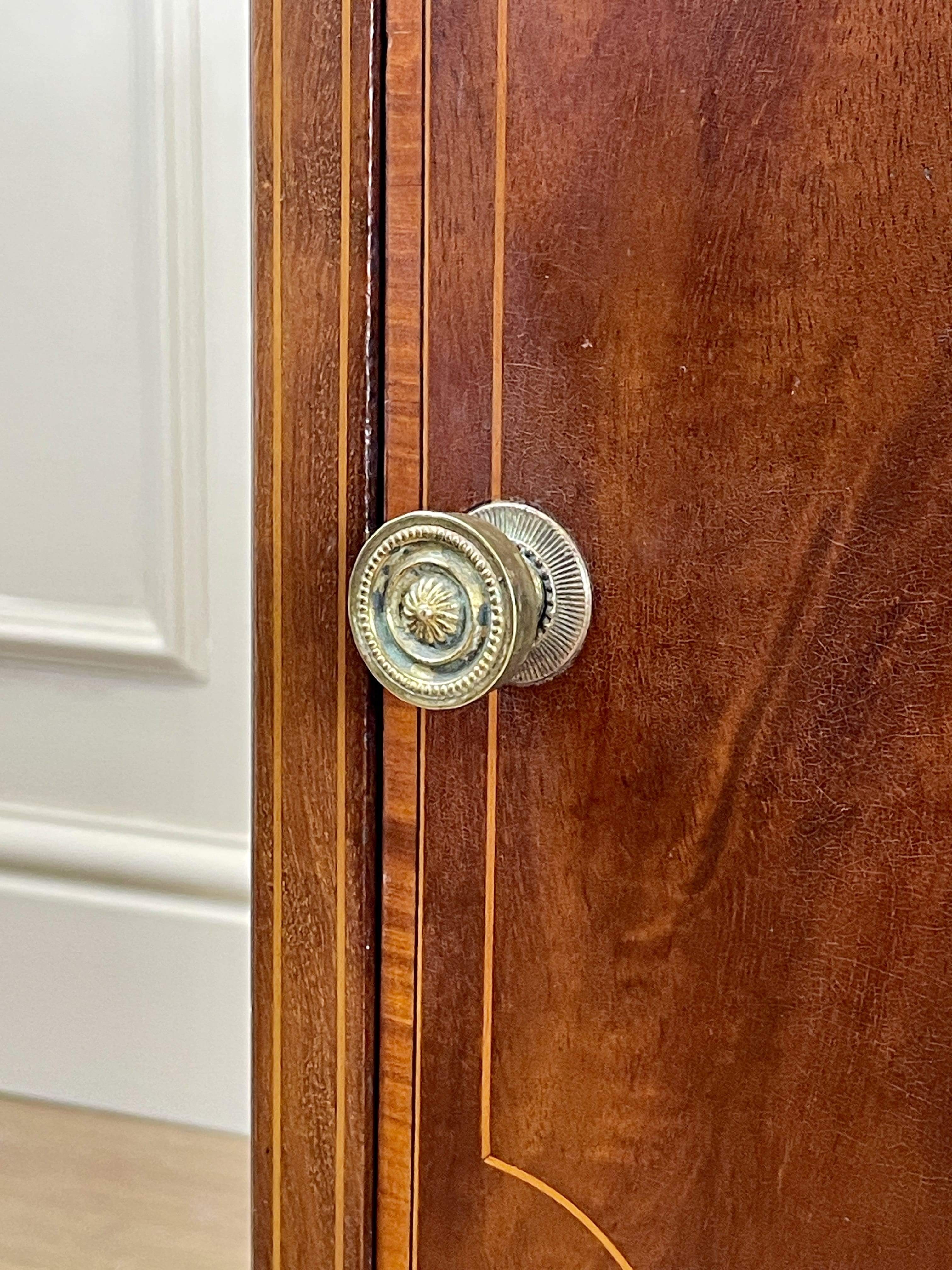 Close-up of a wooden door with brass doorknobs on a white wall background