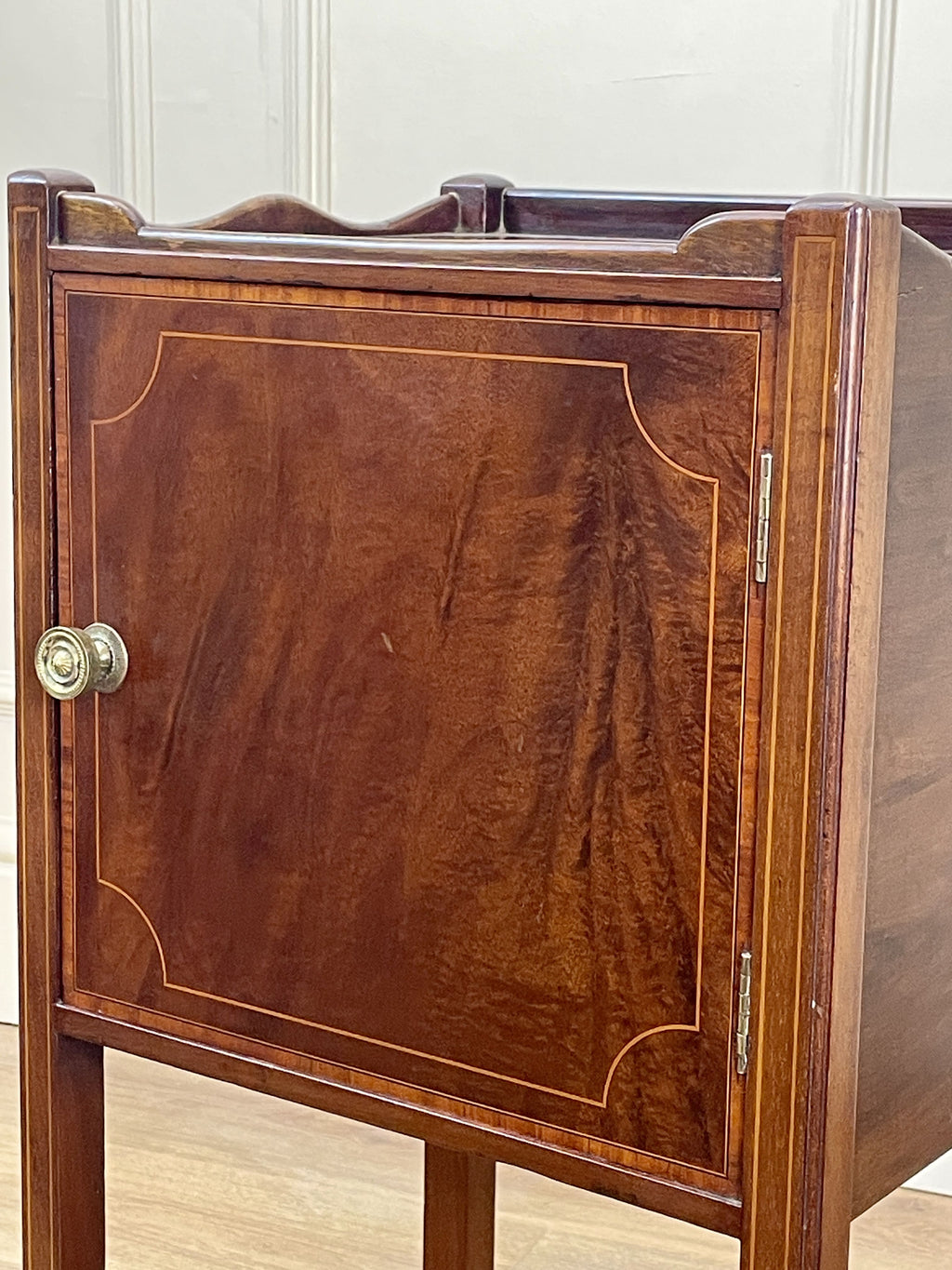 Wooden cabinet with a door and metallic handle on a light wooden floor.