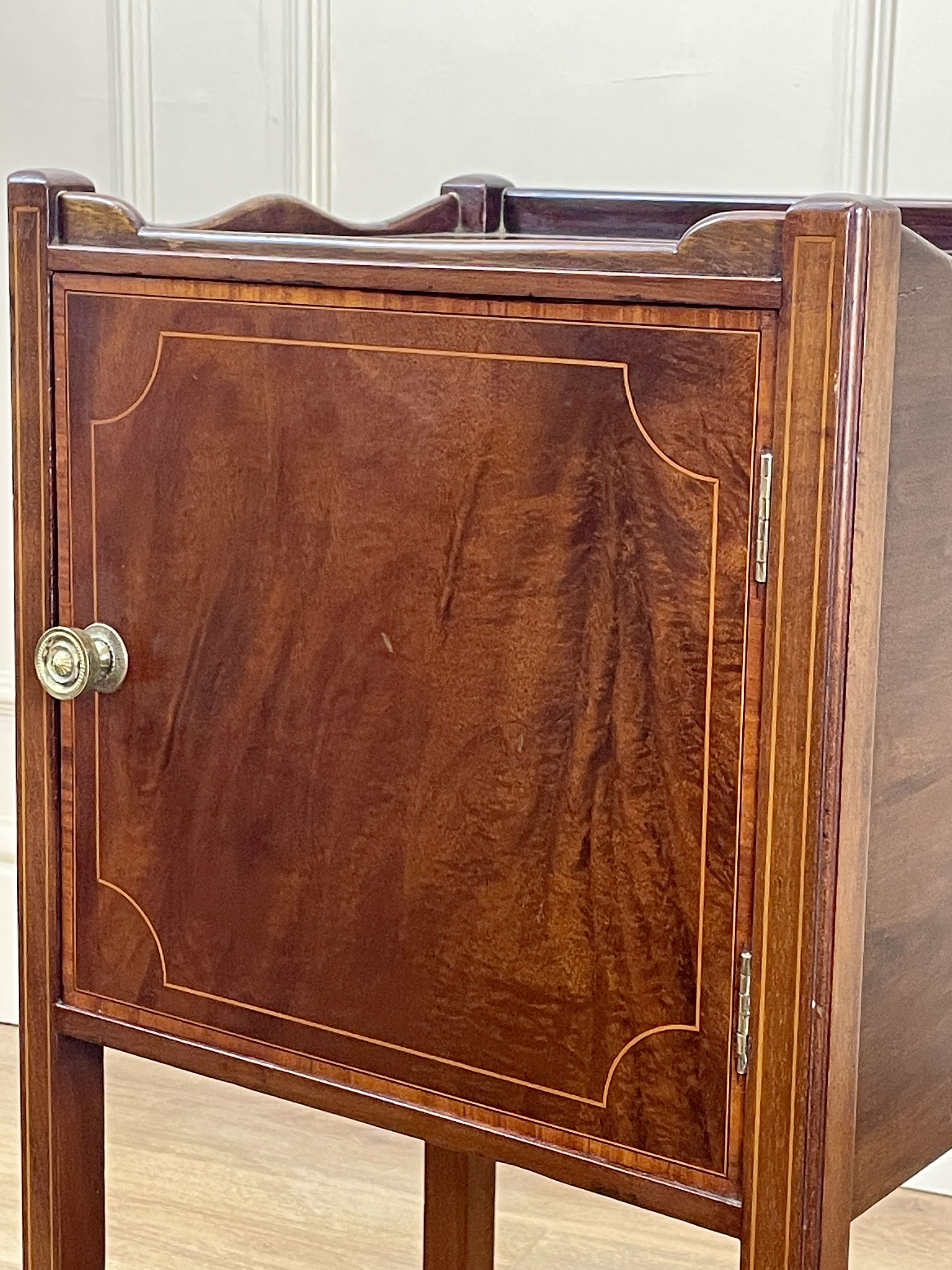 Wooden cabinet with a door and metallic handle on a light wooden floor.