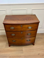 Wooden dresser with three drawers on a wooden floor against a white paneled wall.
