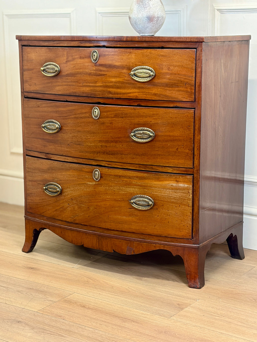 Wooden dresser with four drawers on a wooden floor.