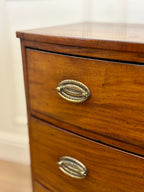 Wooden dresser with brass handles on a plain background