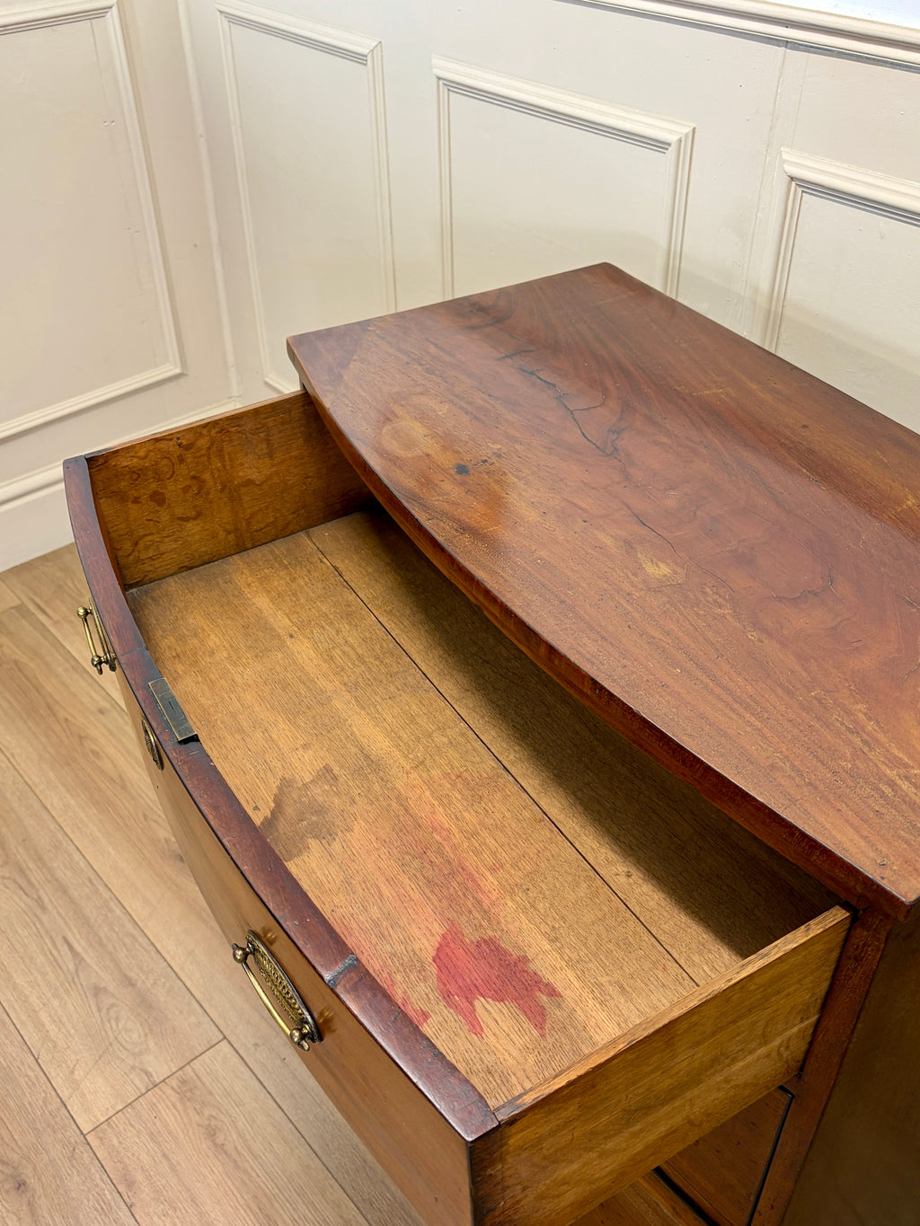 Wooden desk with a drawer open against a white paneled wall.