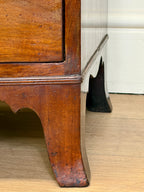 Close-up of a wooden cabinet corner with a white wall in the background