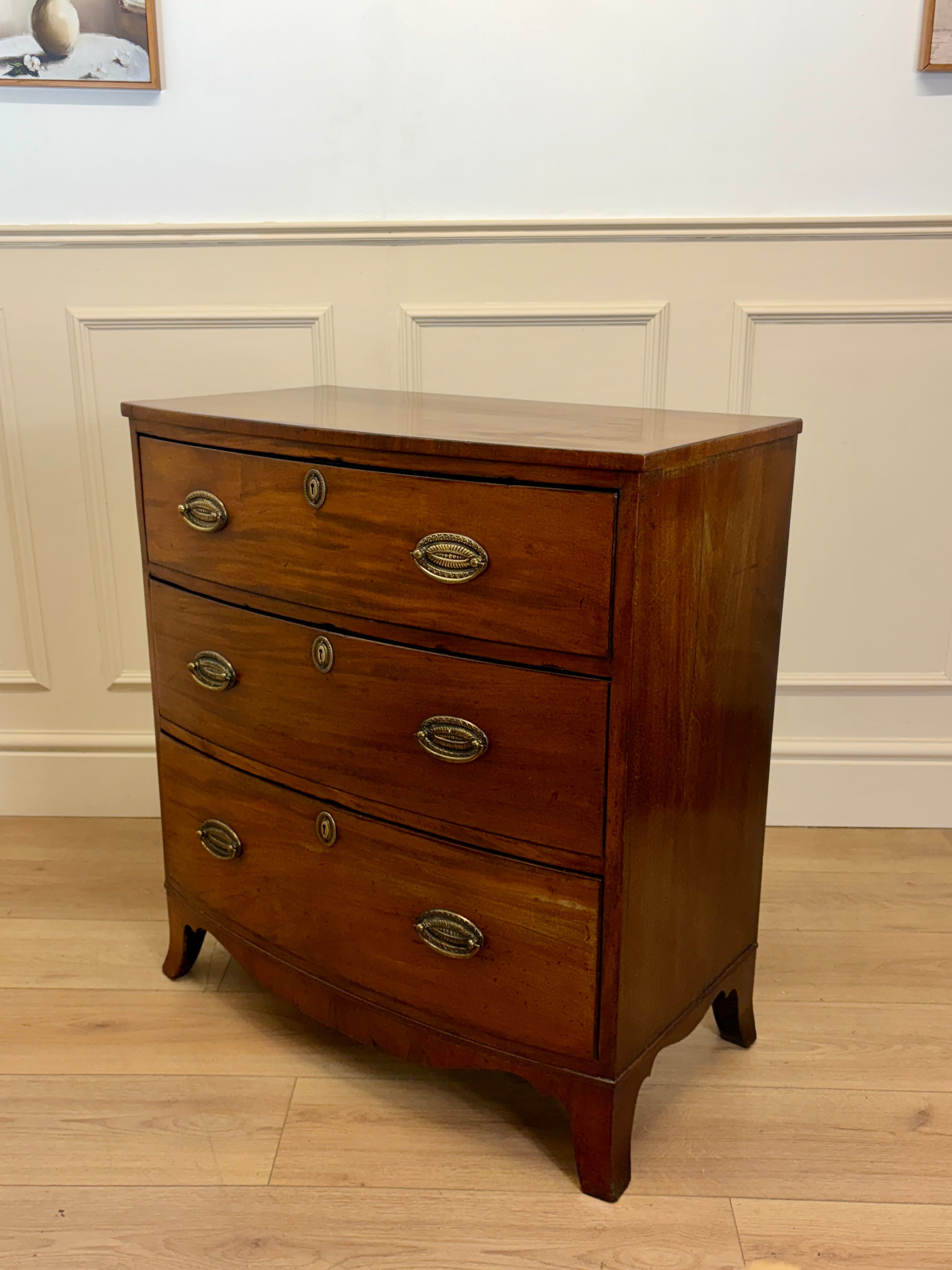 Wooden dresser with three drawers on a wooden floor against a white wall.