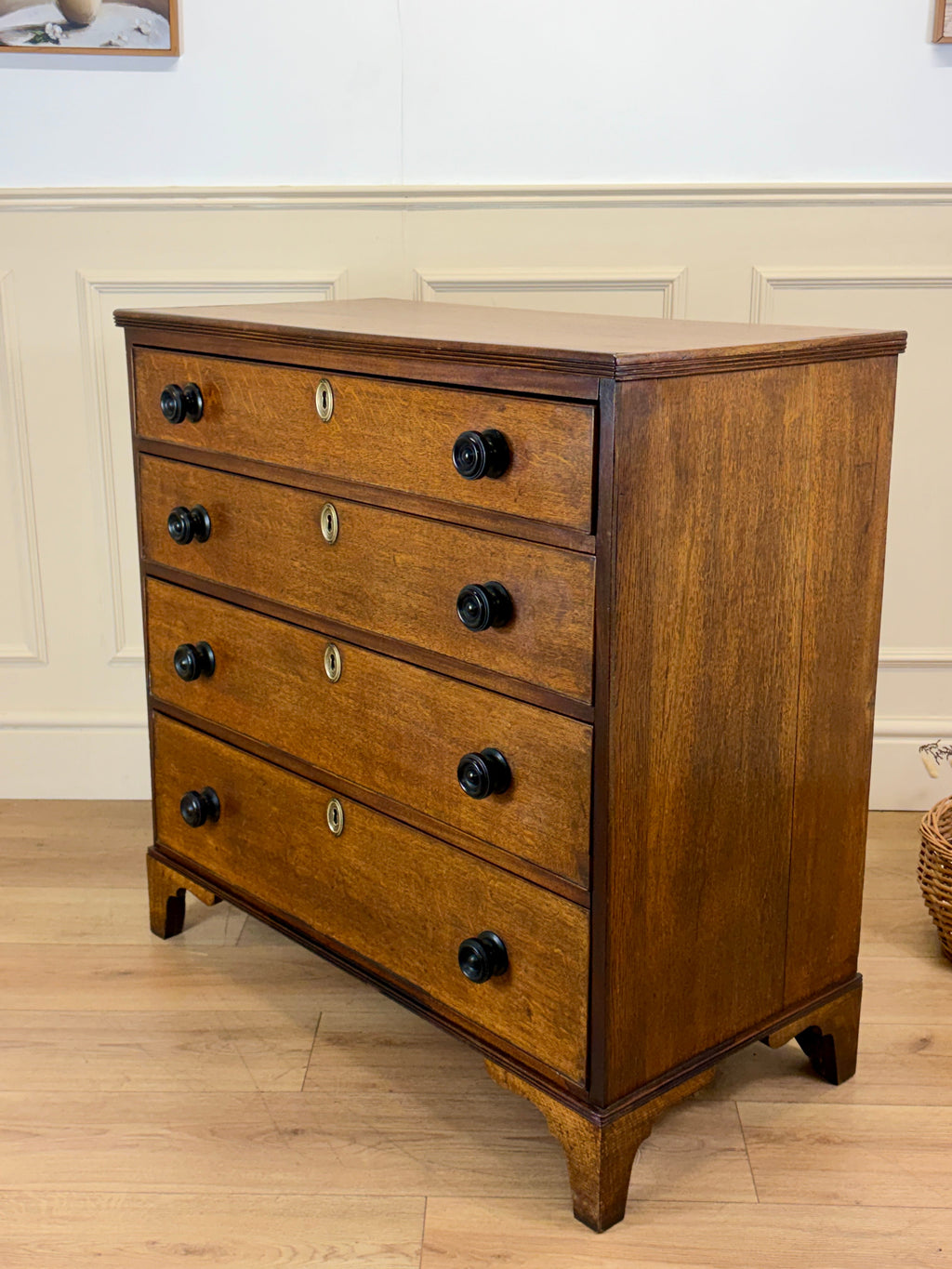 Wooden dresser with four drawers on a wooden floor.