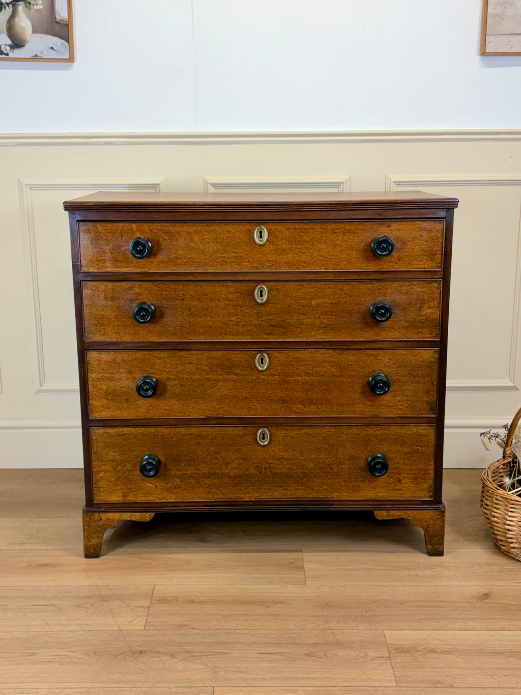 Wooden dresser with four drawers on a wooden floor.