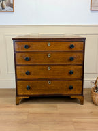 Wooden dresser with four drawers on a wooden floor.
