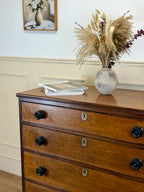 Wooden dresser with decorative items including a vase with dried plants and books.