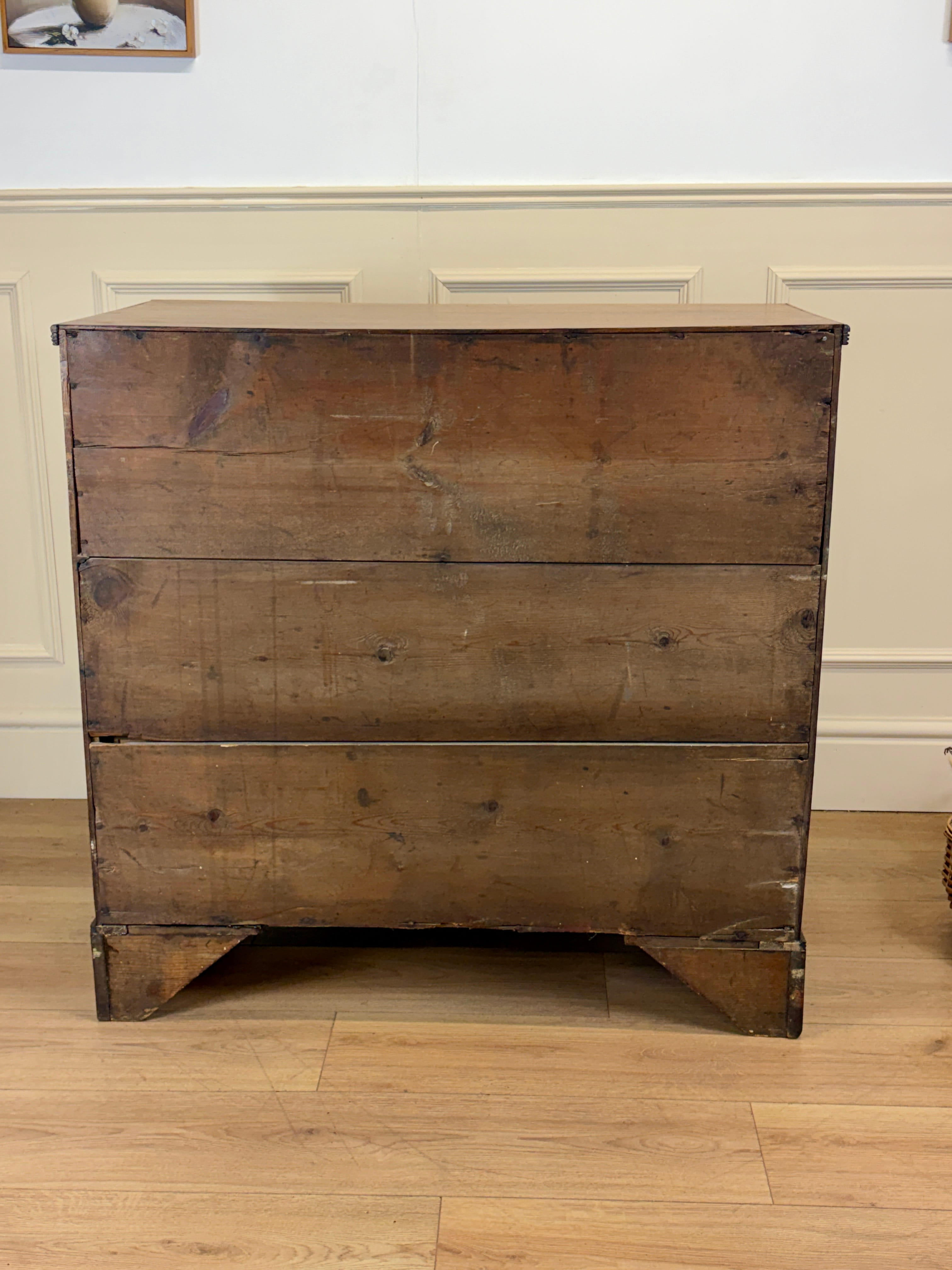 Vintage wooden dresser with chipped paint on a wooden floor.
