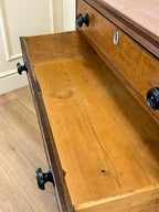 Wooden drawer with black handles on a wooden floor.