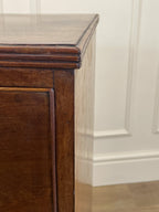 Close-up of a wooden cabinet corner with a white wall background