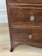 Wooden dresser with brass knobs on a wooden floor.