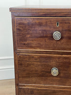 Wooden dresser with brass knobs on a white wall background