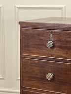 Wooden dresser with brass knobs against a white wall
