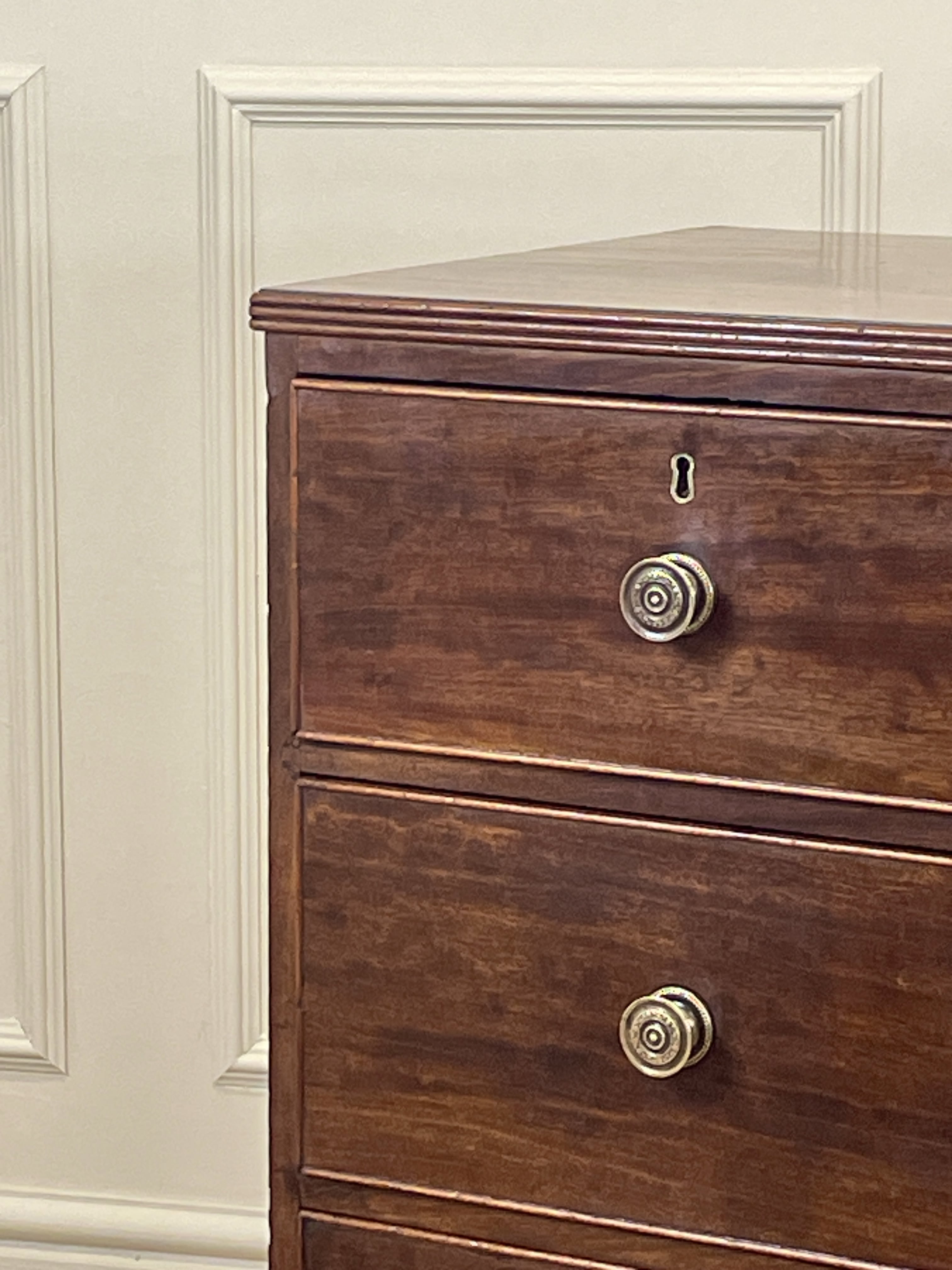 Wooden dresser with brass knobs against a white wall