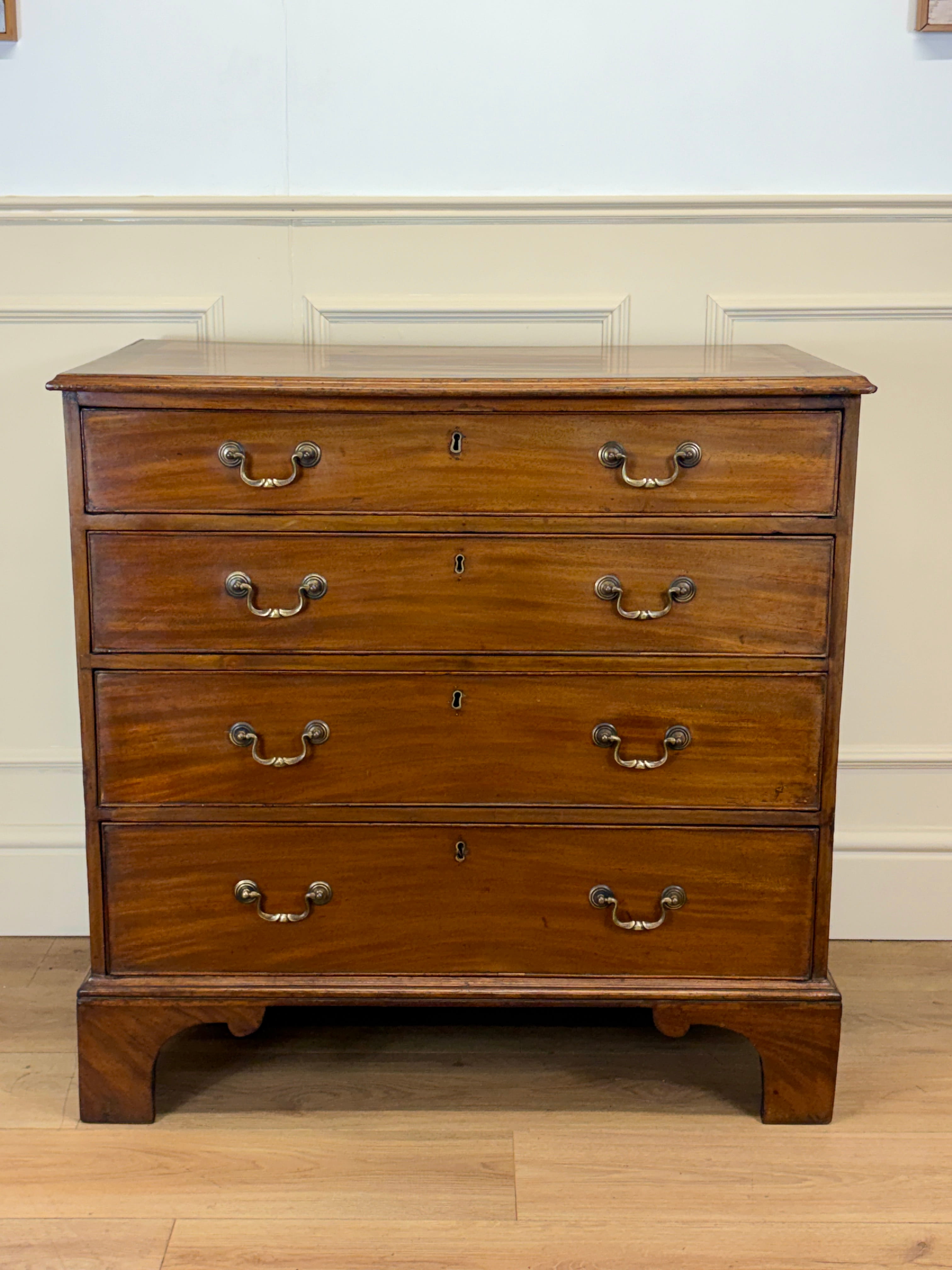Wooden dresser with four drawers on a wooden floor.