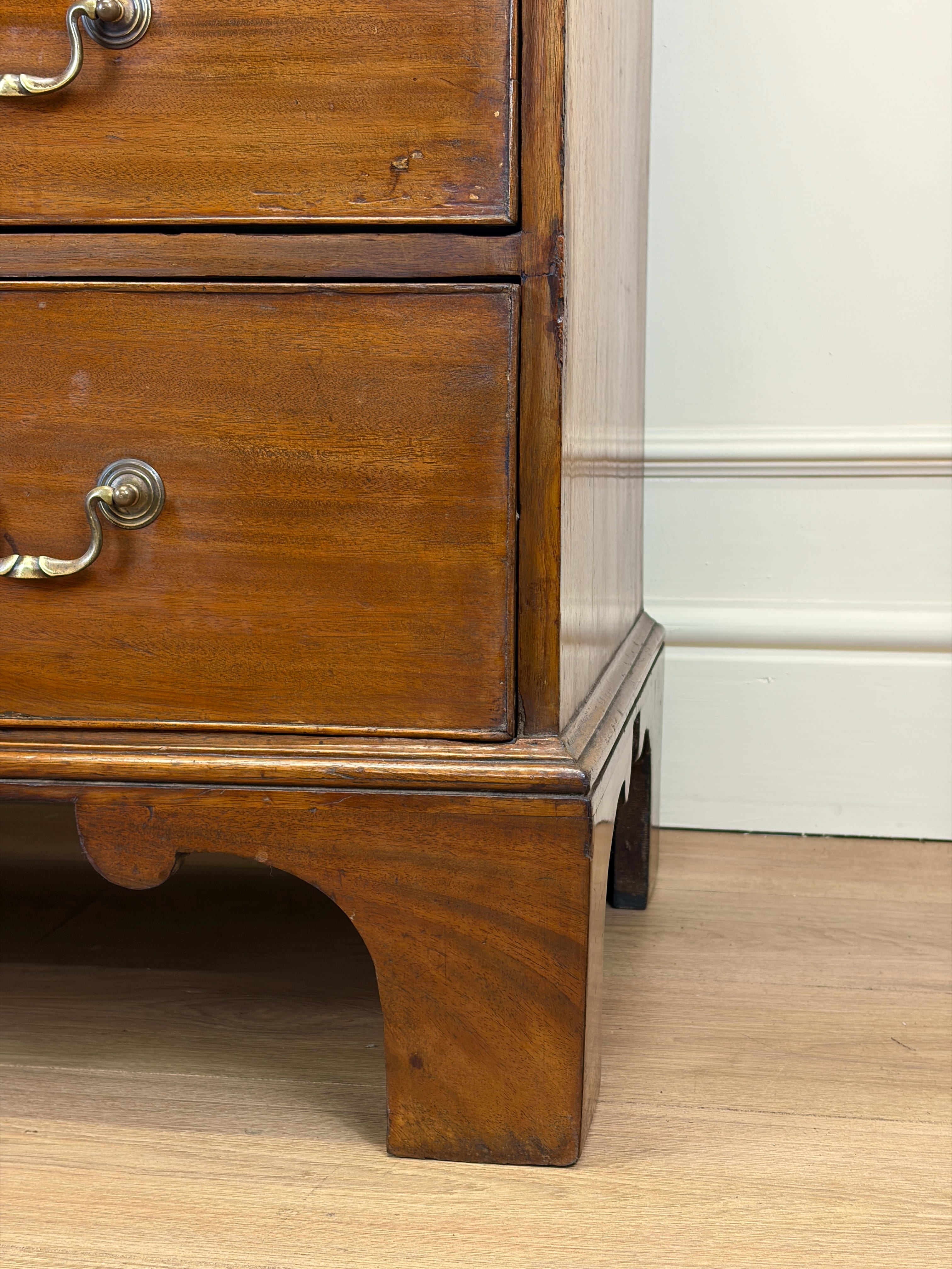 Wooden dresser with brass handles on a wooden floor.