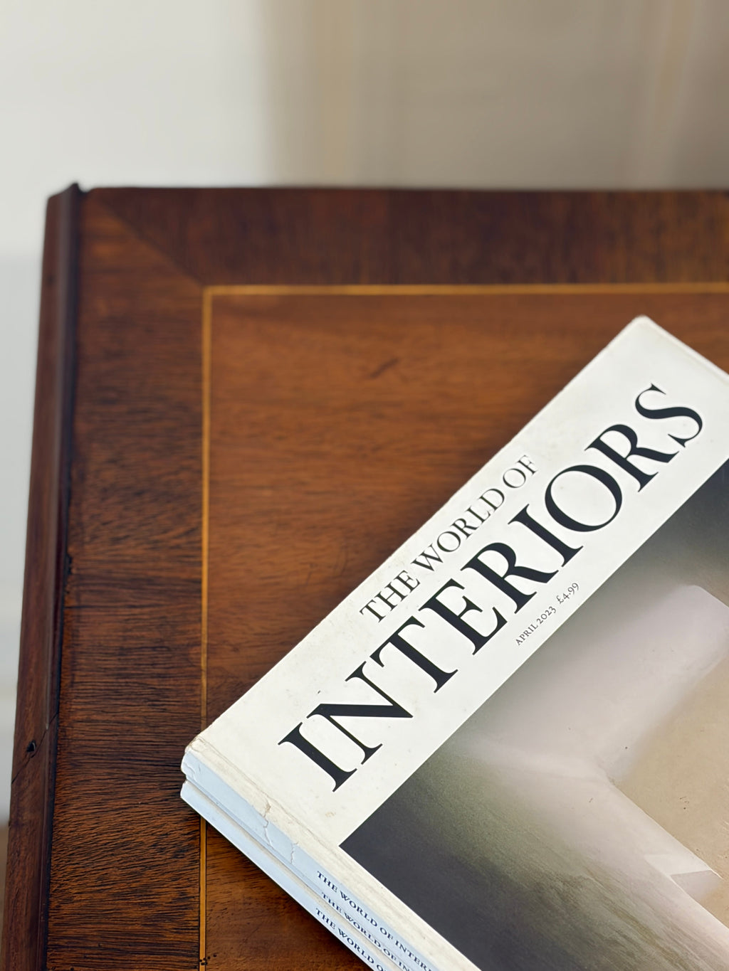 Book titled 'The World of Interiors' on a wooden surface