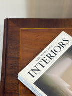 Book titled 'The World of Interiors' on a wooden surface