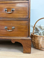 Wooden dresser with two drawers and a wicker basket on a wooden floor.