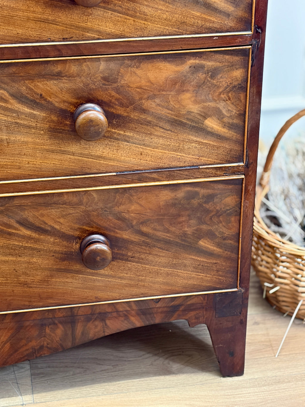 Close-up of a wooden dresser with two drawers and a basket in the background.
