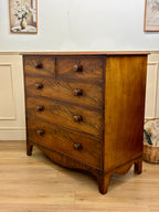 Wooden dresser with four drawers on a wooden floor.
