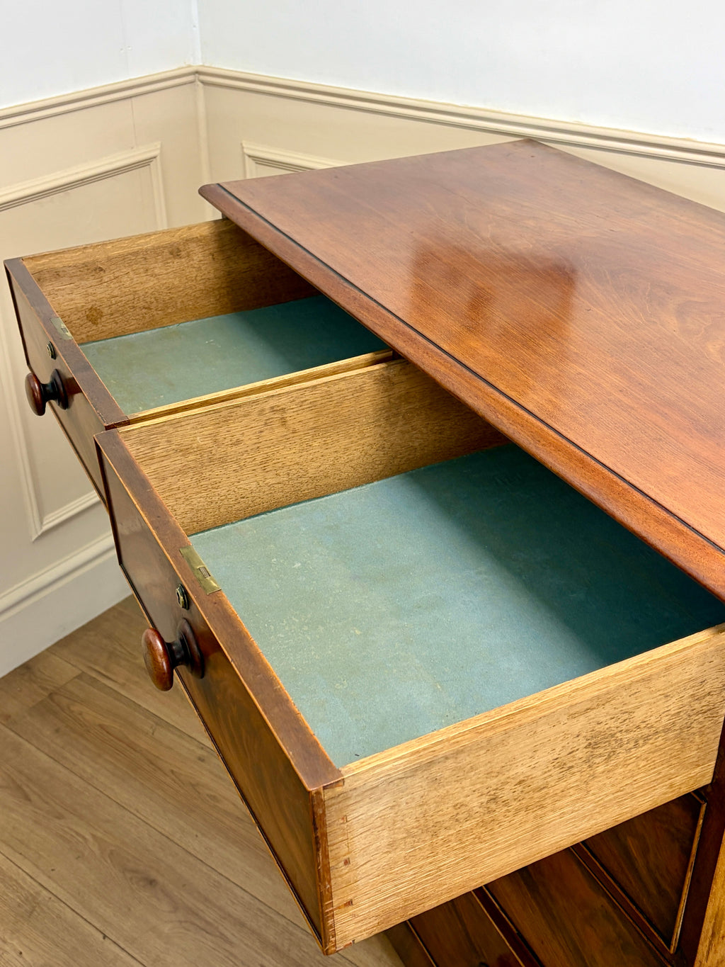 Wooden drawer with a green interior, open on a wooden floor.
