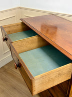 Wooden drawer with a green interior, open on a wooden floor.