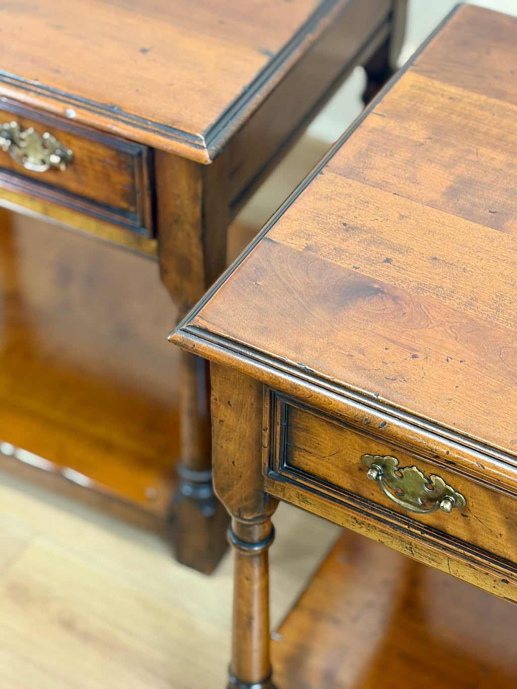 Close-up of a wooden side table with a drawer and decorative handles.
