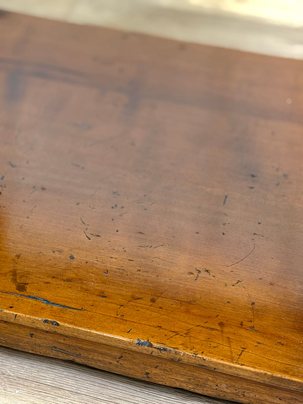 Close-up of a worn wooden surface with visible scratches and scuffs.
